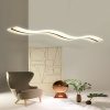 Modern wave-shaped pendant light above an armchair and decorative items in a chic room.