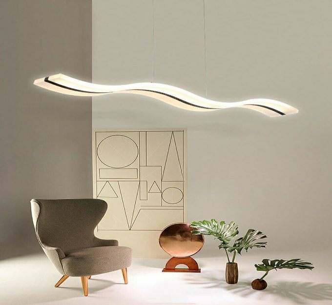 Modern wave-shaped pendant light above an armchair and decorative items in a chic room.