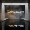 aca014f0-cc21-4561-90de-3a8ed08d7298 Modern abstract light fixture with wavy design reflected in water, set in a minimalist concrete space.