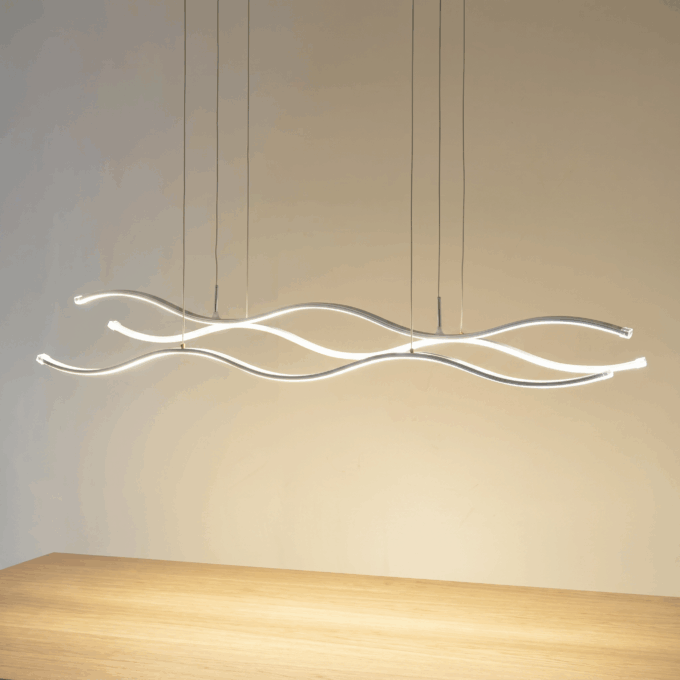 f737290f-7f39-42da-9c6e-9b595b88c226 Modern wavy LED pendant light fixture illuminating a wooden table in a minimalistic interior setting.