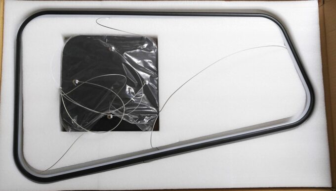 New black computer monitor unpacking with cables and foam padding.