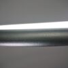 Close-up of modern LED desk lamp with sleek design against a gray backdrop.