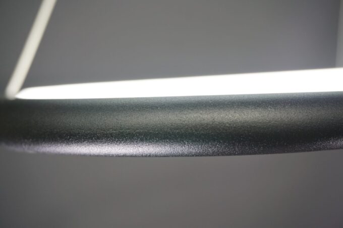 Close-up of modern LED desk lamp with sleek design against a gray backdrop.