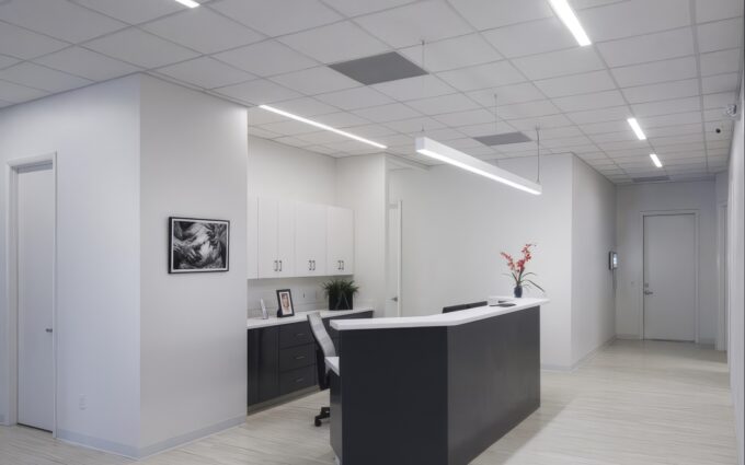 72_397_fr_statesboro_plastic_surgery_web_02 Modern office reception area with white decor, desk, and wall art.