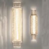 Two modern wall sconce lights illuminated on a gray background.