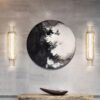 Modern abstract wall art with sconce lights and decorative bowl on marble console.