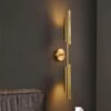 Modern gold wall sconce lighting fixture against dark wall.