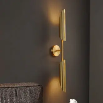 Modern gold wall sconce lighting fixture against dark wall.
