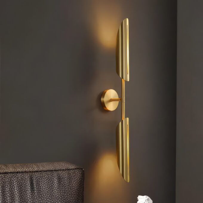 Modern gold wall sconce lighting fixture against dark wall.