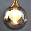 1 Modern suspended pendant light with illuminated bulb inside clear glass orb.