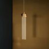 Modern cylindrical pendant light hanging against a dark backdrop.