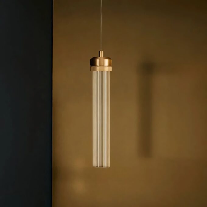 Modern cylindrical pendant light hanging against a dark backdrop.