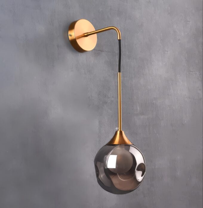 4 Modern gold wall-mounted sconce with a smoky glass globe on a gray background.