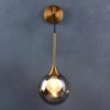 5 Modern gold pendant light with a clear globe against a gray wall.