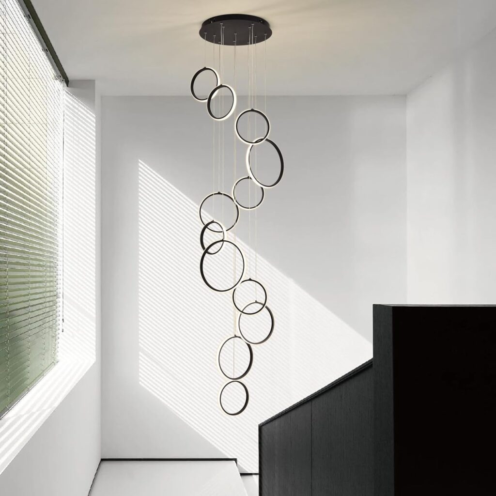 Modern pendant light fixture with circular rings in a minimalistic white room, casting artistic shadows.