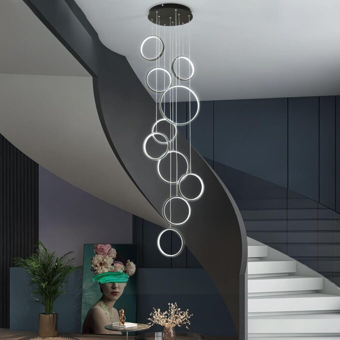 Modern spiral staircase with artistic chandelier, elegant decor, and contemporary art in a stylish interior setting.