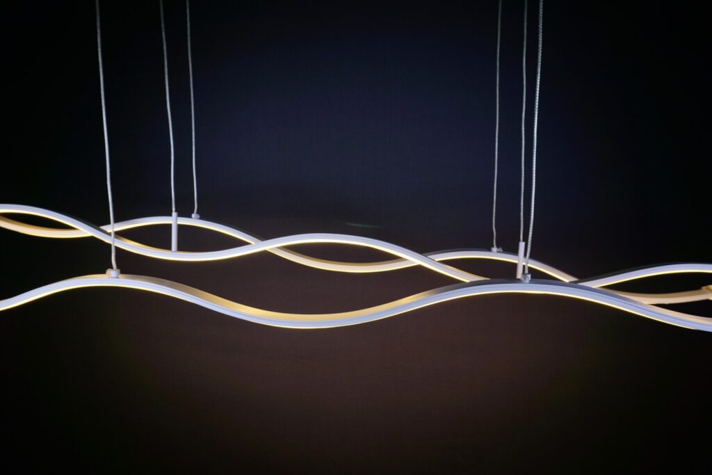 Modern wavy LED pendant light fixture against dark background