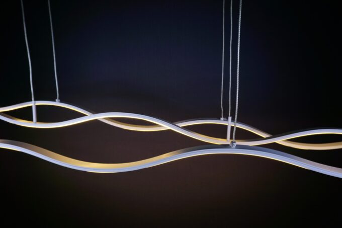 DSC01035 Modern wave-shaped LED pendant light hanging against a dark background.
