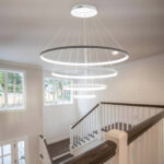 Modern circular LED chandelier lighting in a home interior above staircase.
