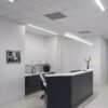 72_397_fr_statesboro_plastic_surgery_web_02 Modern office reception area with white decor, desk, and wall art.