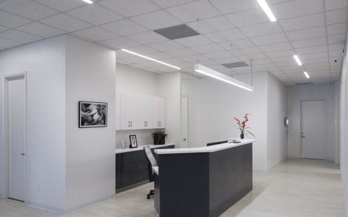 72_397_fr_statesboro_plastic_surgery_web_02 Modern office reception area with white decor, desk, and wall art.