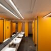 IMG_45091.1 Modern public bathroom with orange partitions and fluorescent lighting.