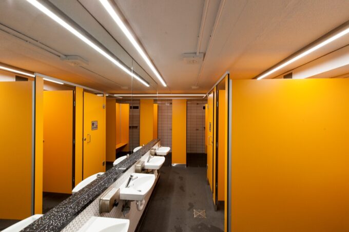 IMG_45091.1 Modern public bathroom with orange partitions and fluorescent lighting.