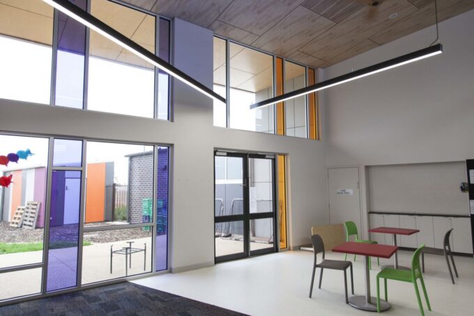 IMG_4881 Modern office break room with colorful chairs, ample lighting, and large windows.