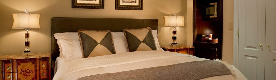 Elegant bedroom with queen-sized bed, antique nightstands, and warm lighting.