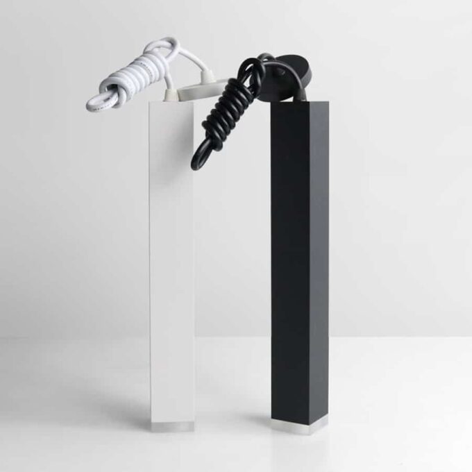 White and black design lamps shaped like knots on pedestals against a plain background.