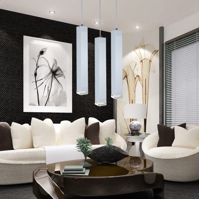 Modern living room with white sofas, pendant lights, and monochrome wall art.