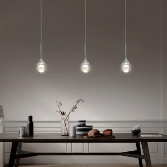 Modern pendant lights over a wooden dining table with decorative items.