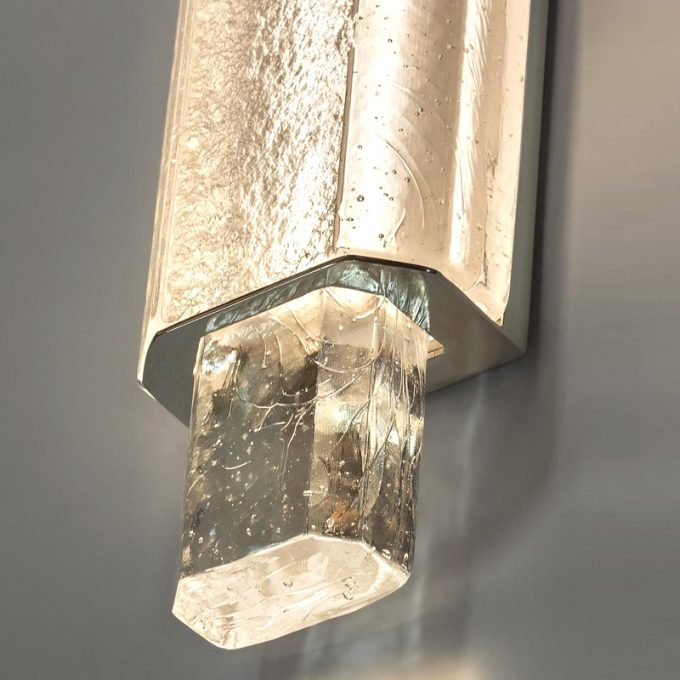 Wall-mounted textured glass sconce with illuminated crystal effect.