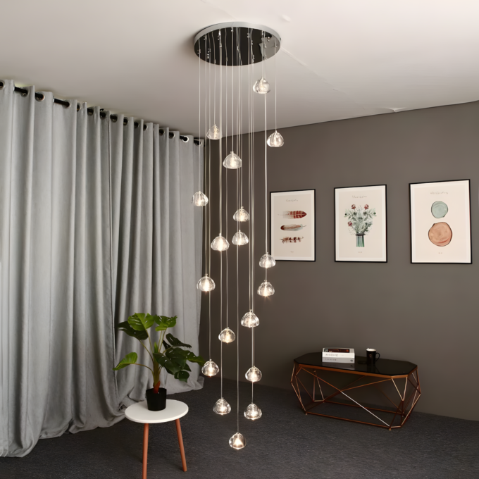 2 Modern living room with chandelier lighting, grey curtains, plant on white side table, and framed art on grey walls.