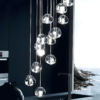 4 Modern pendant lights hanging in a dark kitchen with an ocean view through the window in the background.