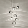 5 Modern glass pendant light fixture with multiple spherical bulbs, hanging elegantly and casting reflections on the wall.