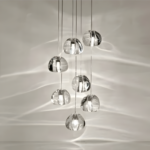 Modern glass pendant light fixture with multiple spherical bulbs, hanging elegantly and casting reflections on the wall.