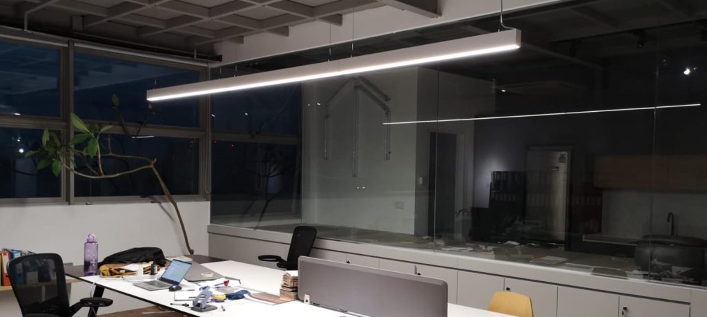 Open Office Space Lit By Linear Pendant Light In A Dark Room