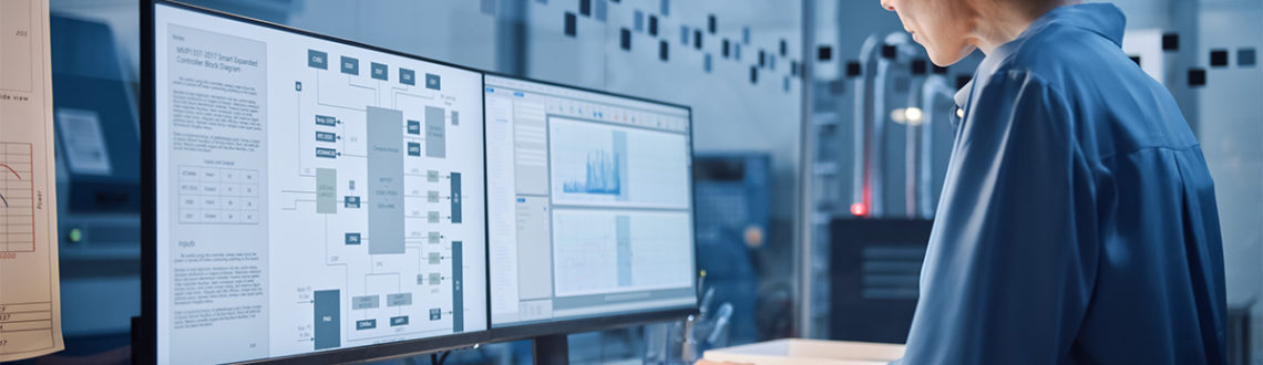 Woman analyzing data on dual computer monitors in a modern office.