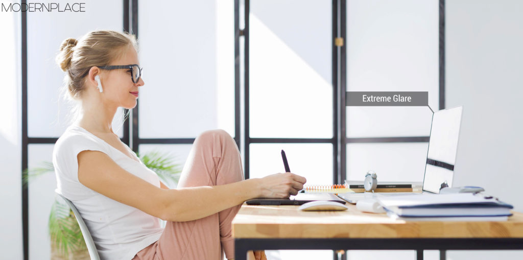 Woman sitting at desk with strong glare on the her laptop