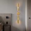 3 Modern gold wall sconce lighting in a contemporary bedroom setting.