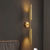 5 Modern gold wall sconce lighting fixture against dark wall.
