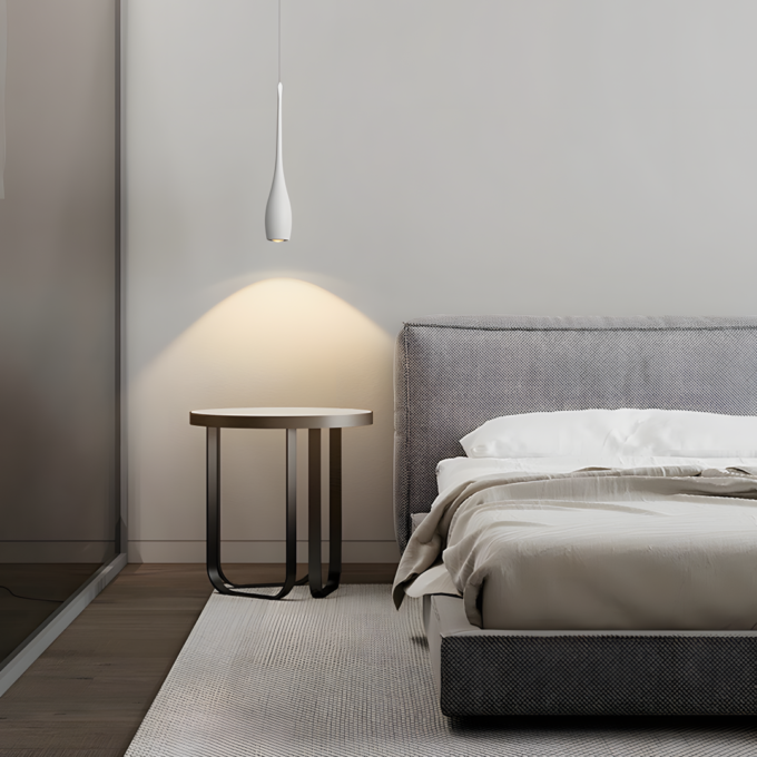 Drop-shapes-pendant-light-1 Modern bedroom with hanging pendant light, side table, and gray bed.