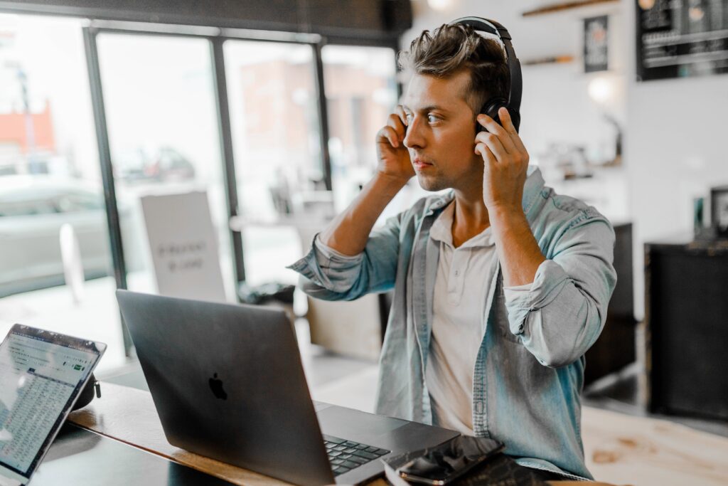 A close-up photo of a LED light fixture with loose wiring and a buzzing sound. man in headphones sitting in office
