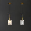 Elegant gold pendant lights with textured glass shades against a dark background.