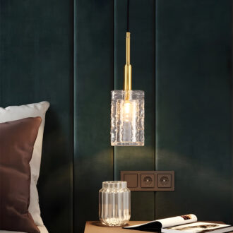 Elegant pendant light with a gold finish and textured glass shade in a dark green room.