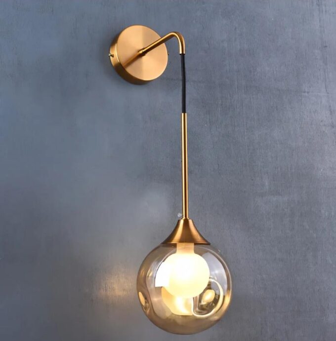 3 Modern gold wall-mounted sconce with glass globe shade.