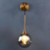 5 Modern gold pendant light with a clear globe against a gray wall.