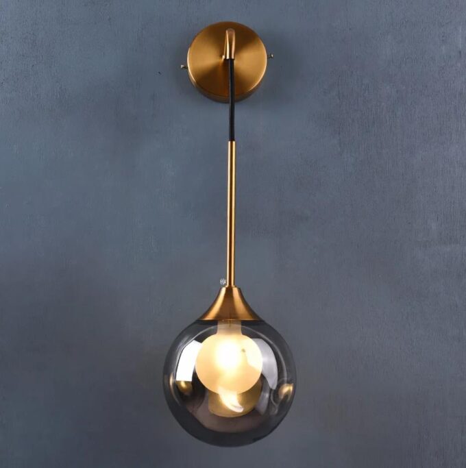 5 Modern gold pendant light with a clear globe against a gray wall.