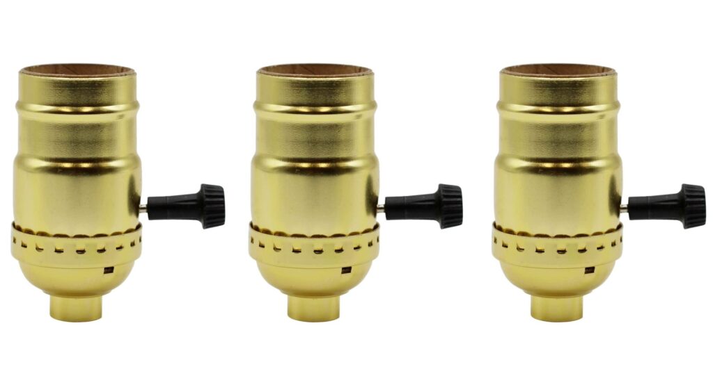 Three brass lamp sockets with rotary switches on white background.